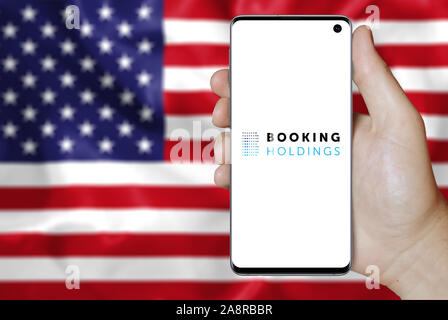 Logo de compagnie publique Booking Holdings Inc affiché sur un smartphone. Pavillon de l'USA historique. Credit : PIXDUCE Banque D'Images