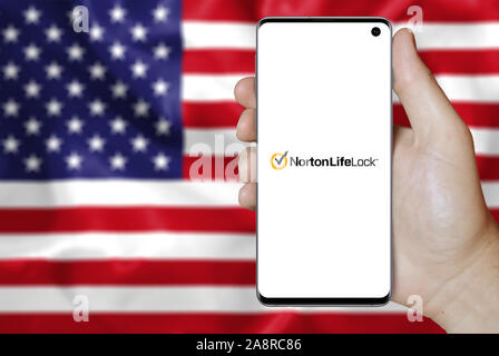 Logo de compagnie NortonLifeLock public affiché sur un smartphone. Pavillon de l'USA historique. Credit : PIXDUCE Banque D'Images