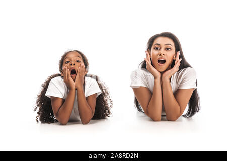 Choqué african american mother and daughter looking at camera while lying on white background Banque D'Images