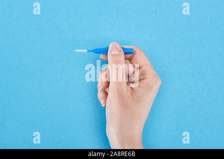 Portrait de femme tenant entre les dents dentaire brosse de nettoyage isolé sur blue Banque D'Images