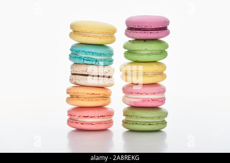 Deux rangées de macarons sucrés français multicolores de différentes saveurs sur fond blanc Banque D'Images