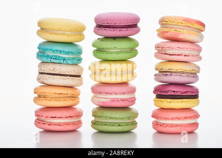 Trois rangées de macarons sucrés français multicolores de différentes saveurs sur fond blanc Banque D'Images