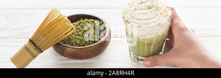 Portrait de femme tenant le matcha thé matcha avec de la crème fouettée sur table avec un fouet, et en poudre Banque D'Images