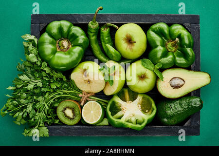 Vue de dessus les pommes, les avocats, les poivrons, les kiwis, de verdure, de la chaux et la courgette dans un coffret en bois Banque D'Images