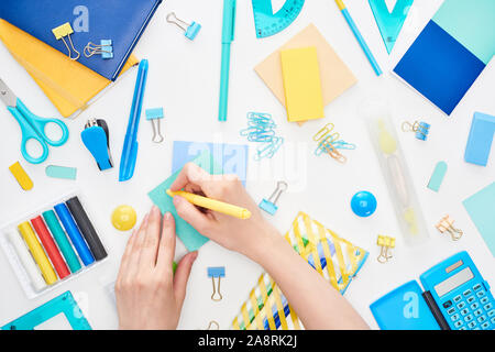 Vue de dessus de l'écriture d'écolière sur carte bleu avec stylo jaune près de la papeterie isolated on white Banque D'Images