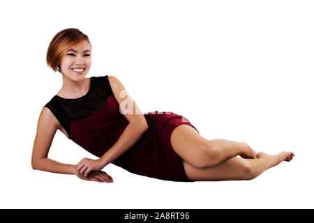 Slim Smiling Asian Woman in red dress couchée sur fond blanc Banque D'Images