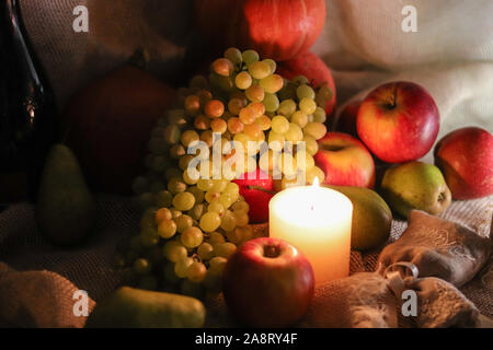 Chasse d'automne. Raisins blancs de sultana, les pommes, les poires et les citrouilles avec des bougies still life sur le sac Banque D'Images