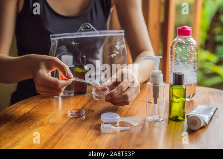 Kit de voyage pour le transport de produits cosmétiques sur un avion. Les cosmétiques sont prêt à être versé dans de petites bouteilles. Une femme passe les cosmétiques de prendre avec elle Banque D'Images