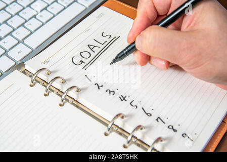 Close-up of a businessman's hand écriture objectifs et liste dans le journal. Banque D'Images