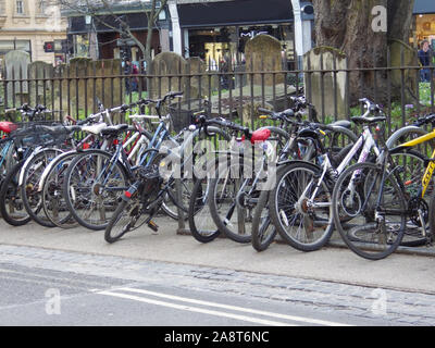 Les vélos des élèves entassés et verrouillé contre vélo se trouve dans le centre-ville d'Oxford à l'extérieur de l'église de Sainte Marie Madeleine avec pierres tombales derrière Banque D'Images