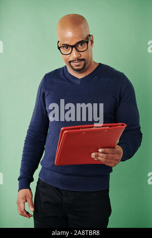 Portrait of handsome convaincu bon entrepreneur holding rouge lumineux dossier Documents and smiling at camera Banque D'Images