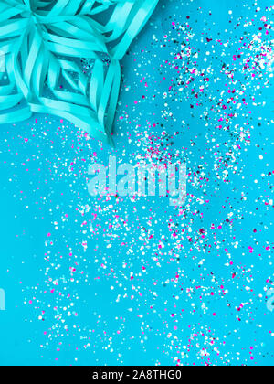 De flocon de papier couleur menthe à la mode, avec des confettis colorés sur fond de couleur bleue. Maison de vacances simple concept. Toile de fête d'hiver. Haut Banque D'Images
