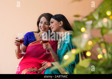 Les femmes en saree boire un verre ensemble Banque D'Images