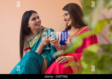 Les femmes en saree boire un verre ensemble Banque D'Images