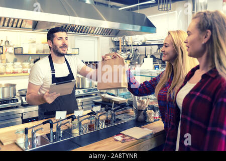 Serveur qui sert de la nourriture à emporter aux clients au comptoir dans petite famille eatery restaurant Banque D'Images