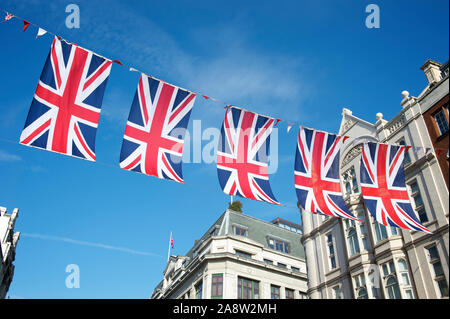 Union Jack flag décorations suspendus au-dessus des rues de Londres, UK contre ciel bleu Banque D'Images