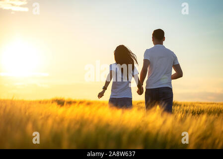 Love Couple fonctionnant en champ d'été romantique Banque D'Images