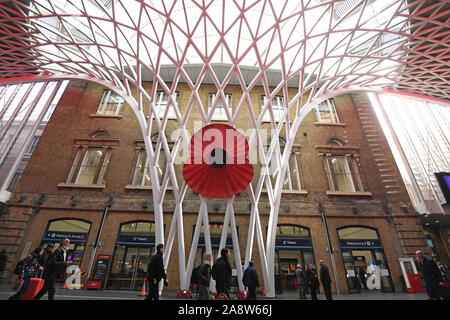 Un grand modèle d'un coquelicot sur King's Cross St Pancras à Londres, comme les gens se rassemblent pour observer un silence pour marquer le Jour de l'Armistice, l'anniversaire de la fin de la Première Guerre mondiale. Banque D'Images