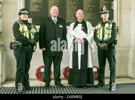 Waterloo London, UK. 11 novembre, 2019. Christopher Henley, Chaplin ferroviaire pose pour des photos avec Andy Mellors, directeur général des chemins de fer du sud-ouest et les membres de la police britannique des transports après avoir dirigé un Armistice Day Service à la gare de Waterloo monument commémoratif de guerre et deux minutes de silence le respect dans le cadre du Jour de l'Armistice qui est célébrée tous les ans le 11 novembre pour marquer la fin de la Première Guerre mondiale et l'armistice signé entre les alliés de la Première Guerre mondiale et l'Allemagne : Crédit amer ghazzal/Alamy Live News Banque D'Images