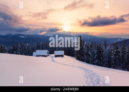 Soirée de Noël paysage avec abris couverts par la neige profonde dans les montagnes Banque D'Images