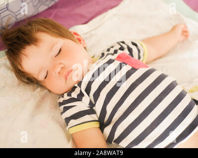 Bébé endormi sur le lit des parents. 0-1 ans Bébé. Portrait d'un nouveau-né dans la chambre des parents. Le sommeil diurne du bébé. Vie insouciante de l'enfance. Le bon sommeil Banque D'Images