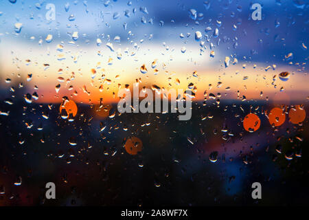 De soleil colorés par la fenêtre en verre humide avec des gouttes perlées et les ruisseaux d'eau sur un jour de tempête dans un contexte conceptuel Banque D'Images