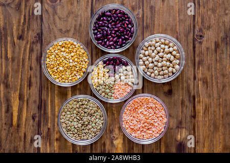 Plusieurs légumineuses dans des bols. Les lentilles, pois, haricots, pois chiches on a wooden background Banque D'Images