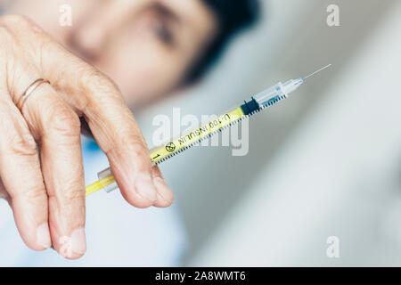 Une main de femme avec une seringue médicale et une bouteille avec de l'insuline pour le diabète sur tableau blanc Banque D'Images