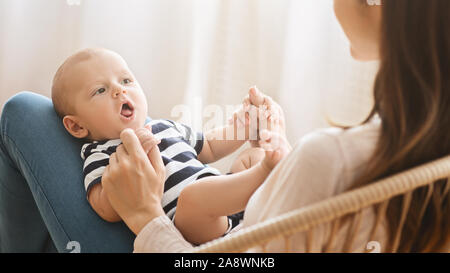 Adorable bébé nouveau-né roucoulement couchée sur les genoux de mère Banque D'Images