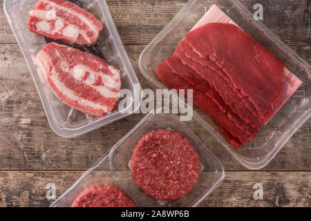 Différents types de viande emballée dans du plastique sur la table en bois. Vue d'en haut Banque D'Images