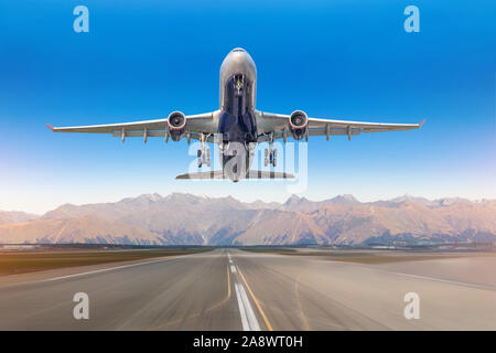 Vue sur la piste de l'aéroport, et d'un décollage d'avions de transport de passagers contre contexte le système de montagne par temps clair Banque D'Images