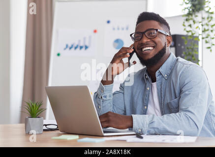 Happy black businessman talking on phone, recevoir de bonnes nouvelles Banque D'Images