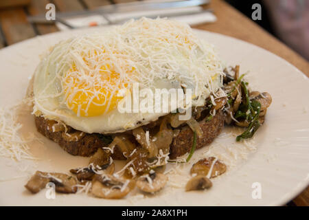 Oeuf frit recouvert de fromage, servi sur du pain de céréales avec champignons rôtis Banque D'Images