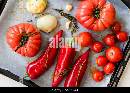 Tomates confites, poivrons rouges, oignons, tomates cerises, d'épices, de romarin et de sel moulin à poivre avec plaque de cuisson et la feuille de papier. L'alimentation biologique. Banque D'Images