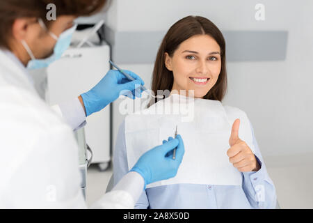 Happy young woman in dentiste président showing thumb up Banque D'Images