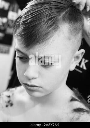 Smiley mignon, beau petit garçon avec TDAH, l'autisme, du syndrome d'Asperger ayant ses cheveux à réaliser dans le salon de coiffure, coiffeur, esthéticienne Banque D'Images