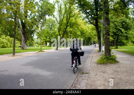 View of man riding bicycle in motion floue, arbres et route à Vondelpark à Amsterdam. C'est un parc urbain de 47 hectares. Il s'agit d'une journée d'été. Banque D'Images