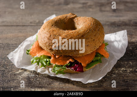 Sandwich bagel au fromage à la crème, saumon fumé et légumes sur table en bois Banque D'Images