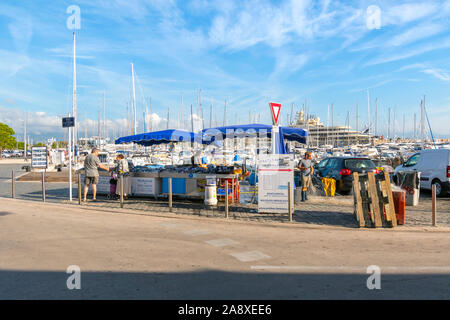 Les pêcheurs locaux à un stand alimentaire vendre du poisson frais avec un port de yachts et bateaux dans le port d'Antibes, France, sur la côte d'Azur Banque D'Images