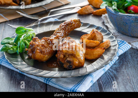 En pilons de poulet au gingembre Sauce avec les quartiers de pommes de terre et de salade sur une assiette Banque D'Images