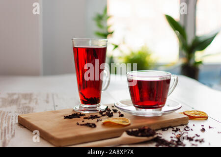 Tasse de thé hibiscus (karkade, red sorrel, Flor de Agua de la Jamaïque) sur une table. Fait à partir de calices magenta (sépales) de fleurs de Roselle. Banque D'Images