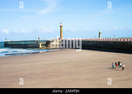 La belle plage de sable, à Whitby, en collaboration avec Sea Wall et l'entrée de l'estuaire de la rivière Esk et phare de North Yorkshire Angleterre UK Banque D'Images