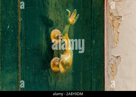 La texture d'une vieille porte en bois en bois avec poignées en métal sous la forme d'un dauphin sur l'île de Malte Banque D'Images