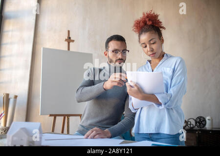 Designer d'intérieur barbu aider son stagiaire avec des croquis Banque D'Images