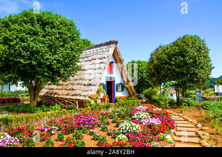 Des maisons traditionnelles en Santana, Madère, Portugal. Maisons en bois triangulaire, représentent une partie de patrimoine portugais. Jardin de devant avec de belles fleurs colorées. Monument touristique. Banque D'Images