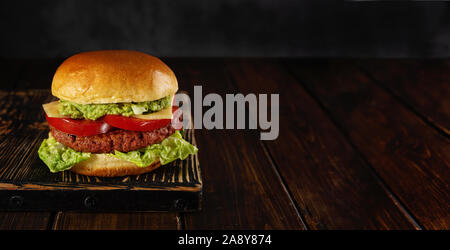 Burger végétarien fait maison sur planche de bois sur fond sombre Banque D'Images