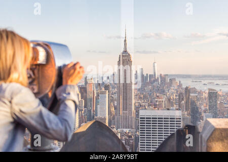 New York, USA - 17 mai 2019 : Rear View of Woman Peering Through Viseur Binoculaire à New York du Haut de la roche Banque D'Images