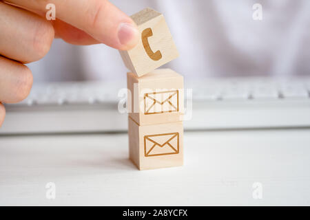 Un homme de main est titulaire d'un cube de bois avec l'image d'un symbole de téléphone. La notion de contacts pour la communication par la communication, comme une meilleure méth Banque D'Images