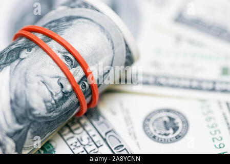 Un rouleau de 100 dollar bills close-up sur un tas de dollars américains. Arrière-plan de billets de 100 dollars américains. Concept financier. Banque D'Images