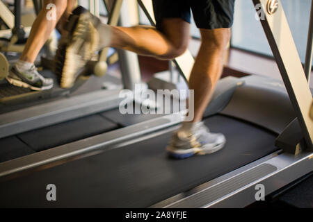 Les jambes d'exécution sur un tapis roulant à l'intérieur d'une salle de sport. Banque D'Images